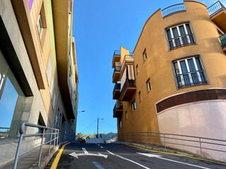 Straße darauf Richtungspfeile, in Valle de San Lorenzo, rechts und links bunte Hausfassaden, blauer Himmel.