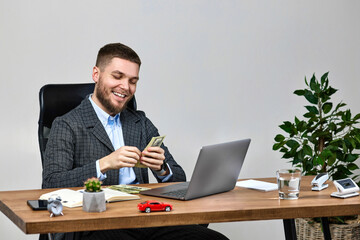 young bearded businessman working on laptop and holding money