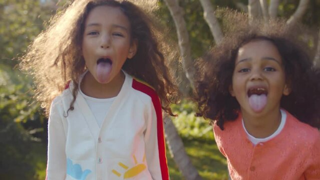 Cute little African-American girls playfully making faces looking at camera. Realtime