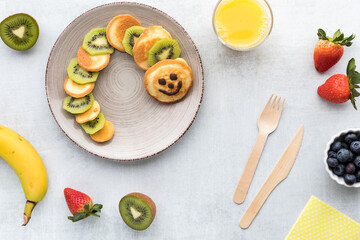 Fun pancakes in the shape of a caterpillar served with fruit and juice.