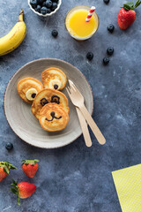 Fototapeta premium Homemade keto diet pancakes in the shape of a bear served with fruit and juice.