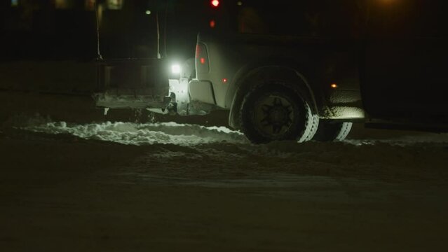 Snow plow truck removing snow in parking lot at night under street lights in snow storm in Colorado winter