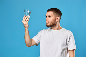 Young guy carefully looks at a glass of water
