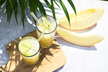 Refreshing melon smoothie with ice and lime in the sun. Summer cooling drinks.