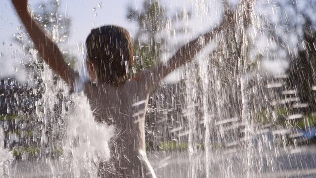 Carefree 6 year old boy dances, spins, splashes at community splash pad