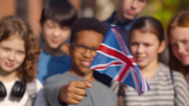 Group of diverse school children with British flag posing at camera. Realtime