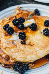 stack of pancakes with blackberries, maple syrup, butter