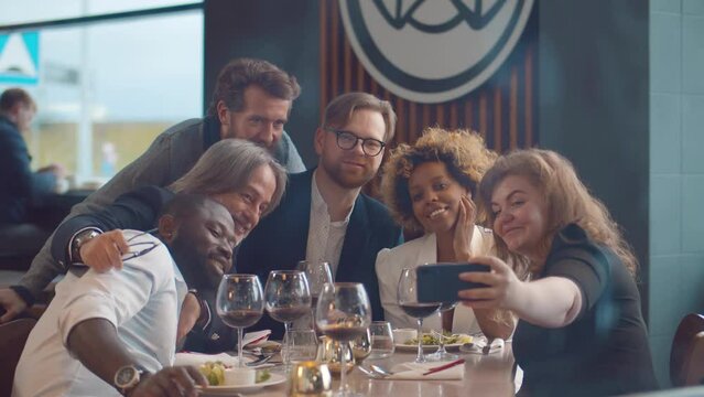 Happy woman takes selfie of herself and her best friends in restaurant. Realtime