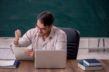 Young male teacher sitting in the classroom