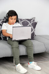 9-year-old Hispanic boy plays video games on his laptop with headphones leading to being overweight...