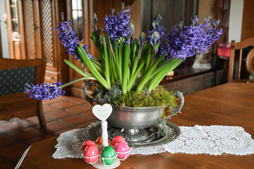 large pewter vase with purple hyacinths on a table in the hall in a rustic style
