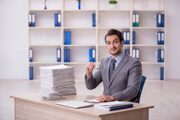 Young male employee and too much work at workplace