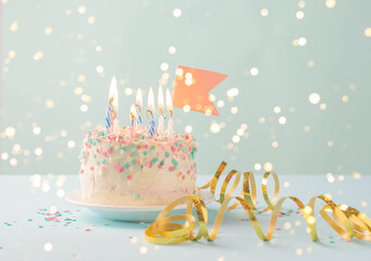 Festive cake with candles on blue background, sequins serpentine, confetti. concept of holiday