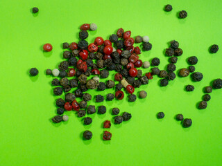 Peppercorns on a green background. Red, white and black peppercorns.  concept of natural cuisine. Seasoning for dishes. The concept of spicy food. Spicy condiment. Cooking.