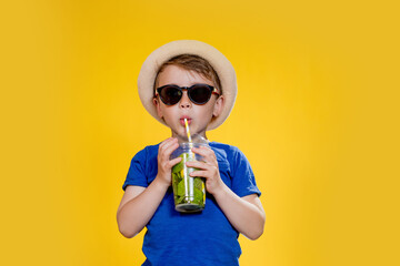 Cute boy Drink Mojito cocktail From Plastic Cup Over Yellow Studio Background