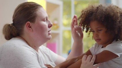 Caucasian woman babysitter try to calm down naughty African-American girl. Realtime