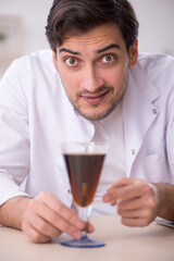 Young male chemist examining soft drink