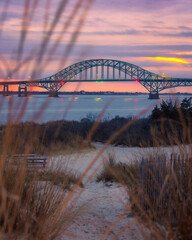 Colorful pastel dusk sky behind a long steel tied arch bridge. Fire Island Inlet Bridge, Captree State Park New York