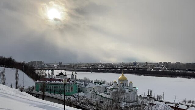 View from Fedorovsky Embankment in Nizhny Novgorod at the Annunciation Monastery in the foreground and the icy Oka river, the Metro Bridge and the Lower City in the background under a dim winter sun