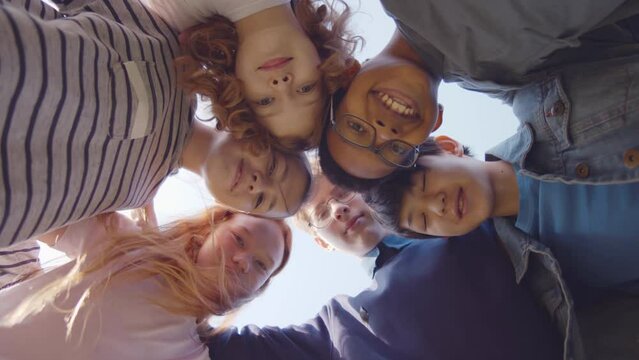 Bottom view of high school students look down at camera in circle. Realtime