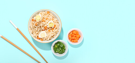 Bowl of tasty Chinese noodles with eggs and vegetables on light blue background with space for text