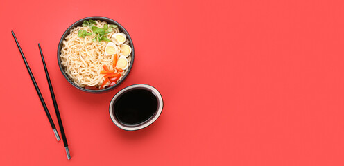 Bowl of tasty Chinese noodles with soy sauce on red background with space for text