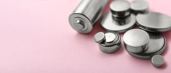 Different batteries on pink background, closeup. Banner for design