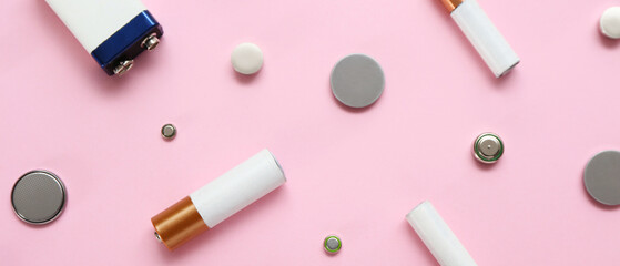 Different batteries on pink background, top view