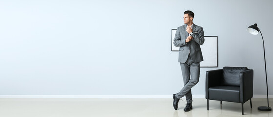 Handsome businessman in formal suit near light wall in room. Banner for design
