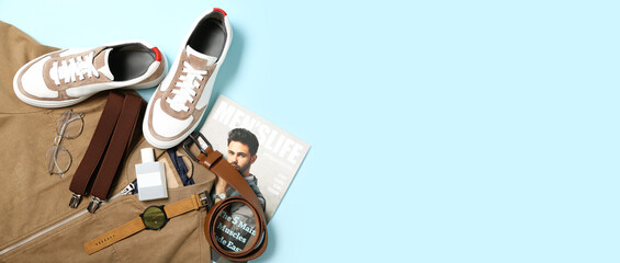 Stylish man's look with suspenders and fashion magazine on light blue background with space for text