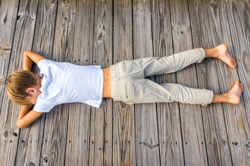 Young Preteen Boy Laying on Boardwalk in the Sun