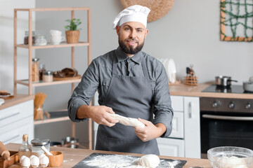 Male baker preparing dough at table in kitchen