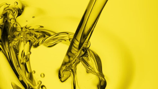Macro crane shot of chamomile oil is being poured into yellow oil on yellow background | Abstract skin care cosmetics ingredients formulating concept