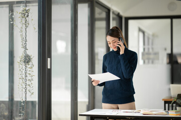Asian business woman Stand on the phone and talk to colleagues or customers.