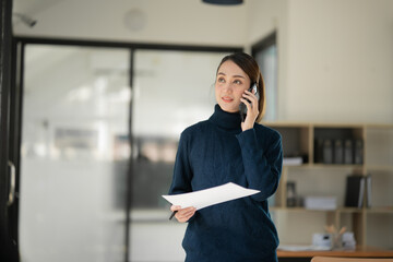 Asian business woman Stand on the phone and talk to colleagues or customers.