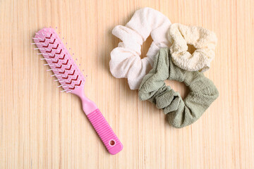 Scrunchies and hair brush on wooden background