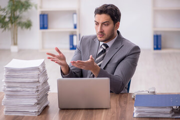 Naklejka premium Young male employee and too much work in the office