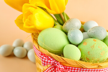 Obraz na płótnie Canvas Basket with beautiful Easter eggs and tulip flowers on color background, closeup