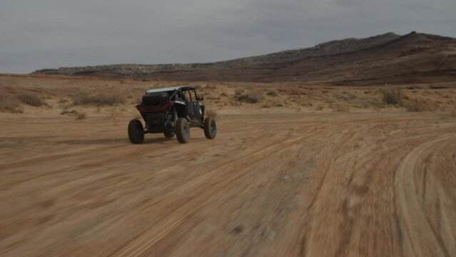 Tracking shot behind UTV driving in sunny Utah desert landscape in sand wash