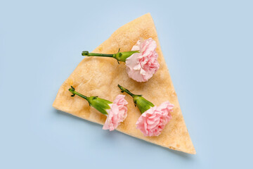 Slice of pizza with beautiful carnation flowers on light background