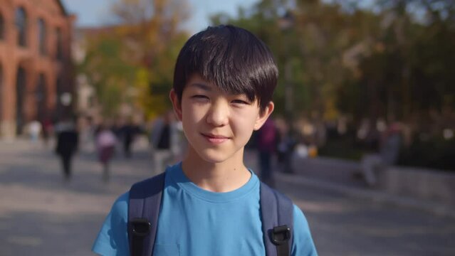 Happy asian teen boy smile at camera outdoors. Realtime