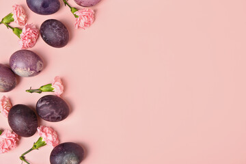 Composition with painted Easter eggs and carnation flowers on pink background