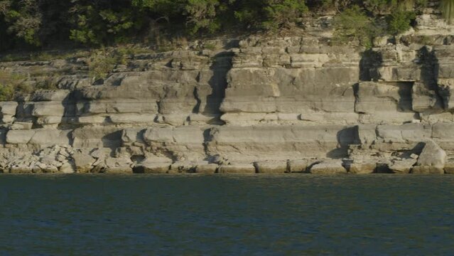 Panning on stone wall in background of Lake Travis in Texas at sunset