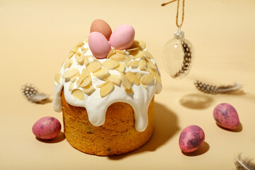 Easter cake, painted eggs and decorations with feathers on beige background