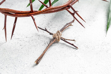 Wooden cross with crown of thorns on white background, closeup. Good Friday concept