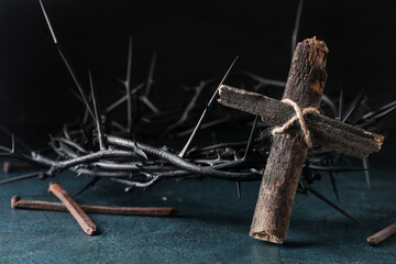 Wooden cross, crown of thorns and nails on dark background. Good Friday concept