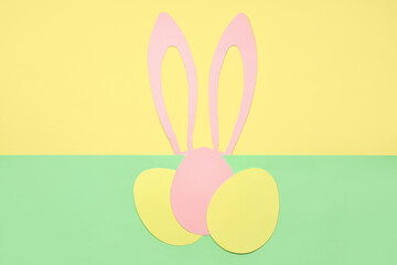 Composition with paper bunny ears and Easter eggs on color background