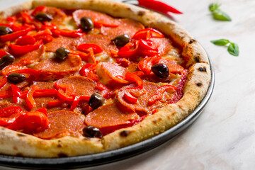 Pepperoni pizza with olives and red pepper on marble table macro close up