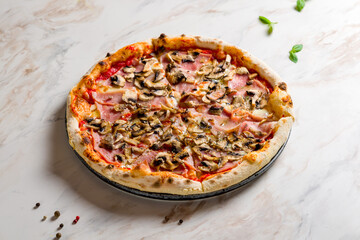 Pizza with ham and mushrooms with tomato sauce on white marble table