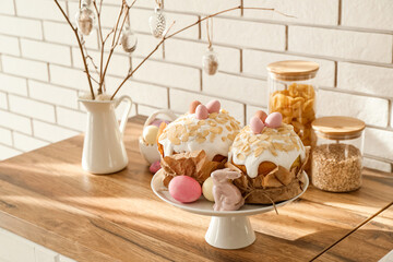 Stand with Easter cakes, painted eggs and bunny on kitchen counter